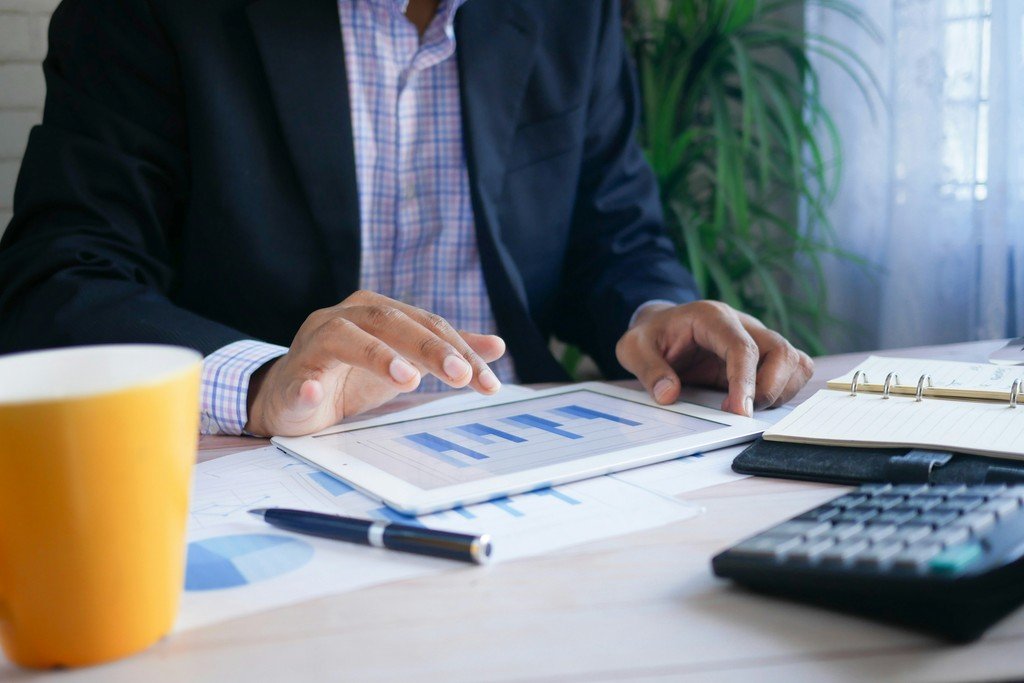 Person in a suit reviewing financial charts and a payment plan on a tablet
