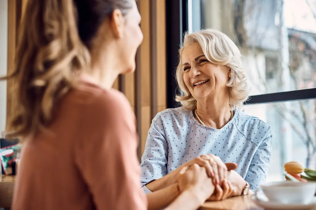 Two women having a warm, close conversation across a table, illustrating the everyday communication that speech audiometry helps protect