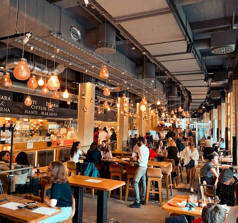 A crowded, noisy restaurant filled with diners at tables, the kind of challenging listening environment assistive listening devices help with