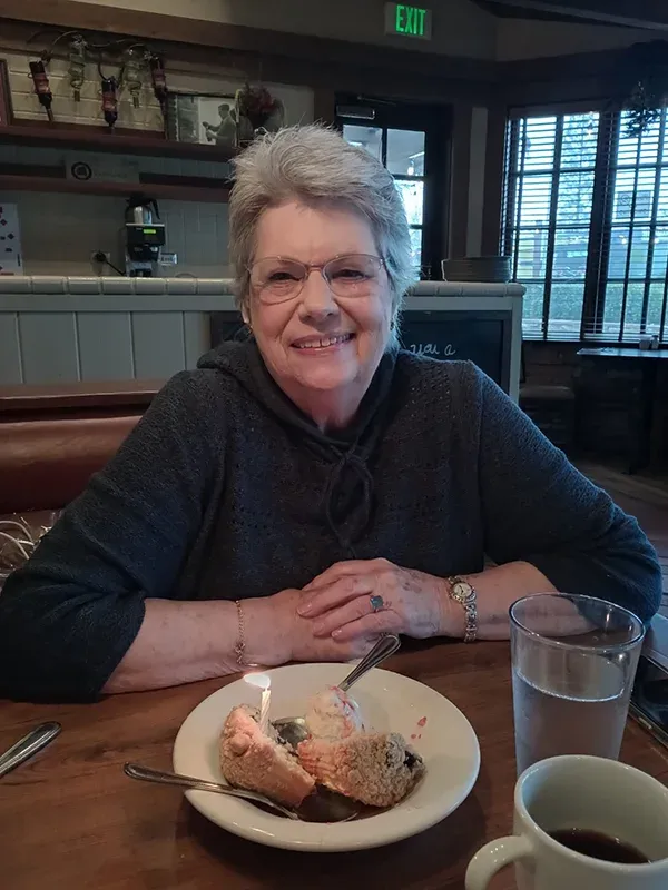 A smiling patient enjoying a celebratory dessert with family at a restaurant